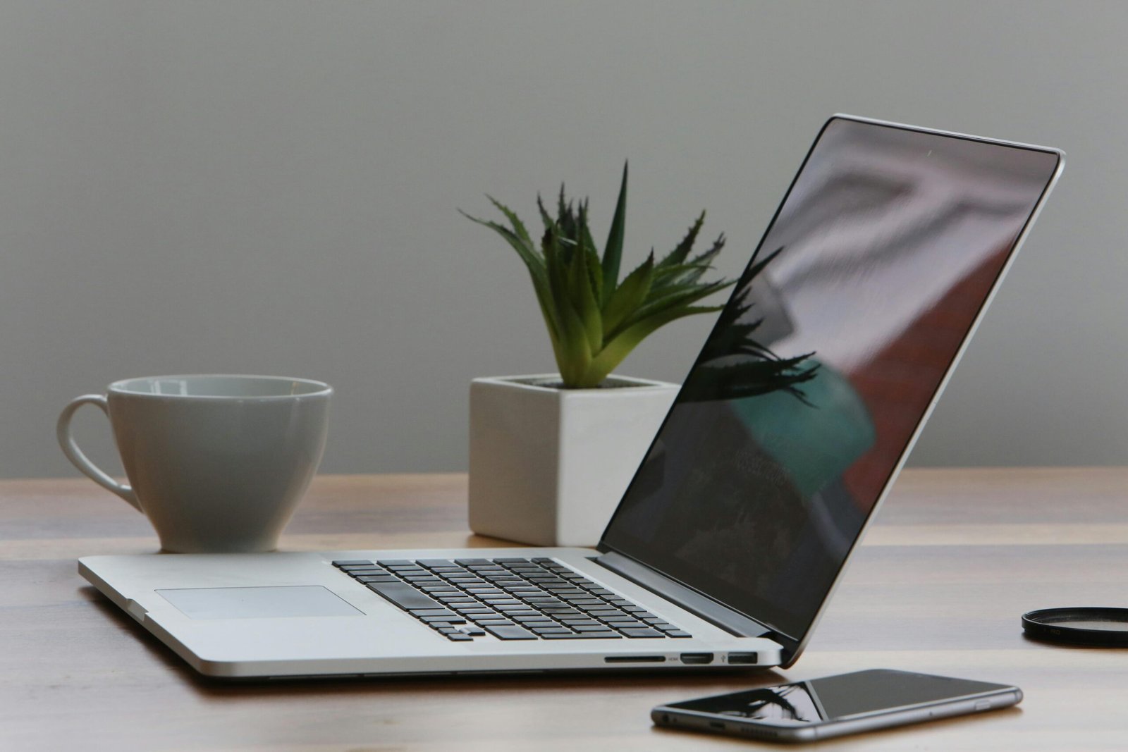 laptop on a table with cup and mobile phone