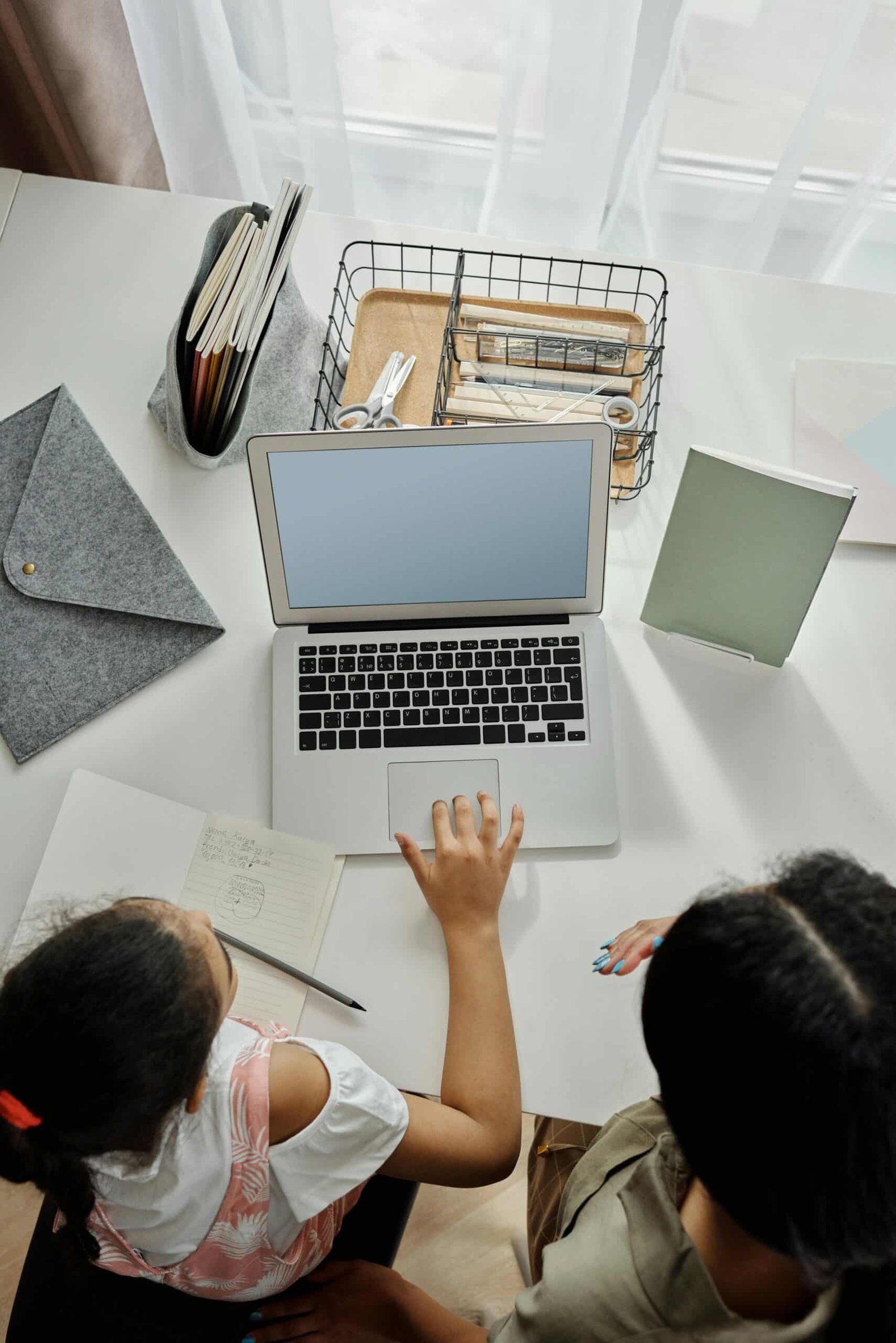 Overhead view of a mother helping her daughter how to use laptop for homework